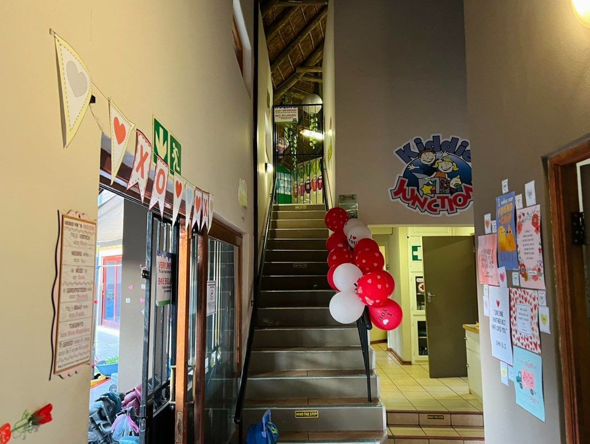 Interior hallway with stairs decorated with red and white balloons. Banners and artwork adorn the walls.