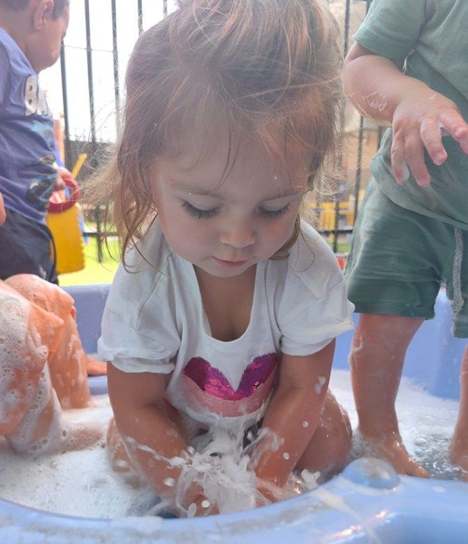 Child playing with bubbles in a small pool, outdoors.