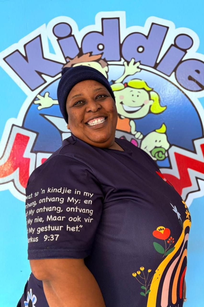 Woman smiling, wearing a navy blue shirt in front of a 