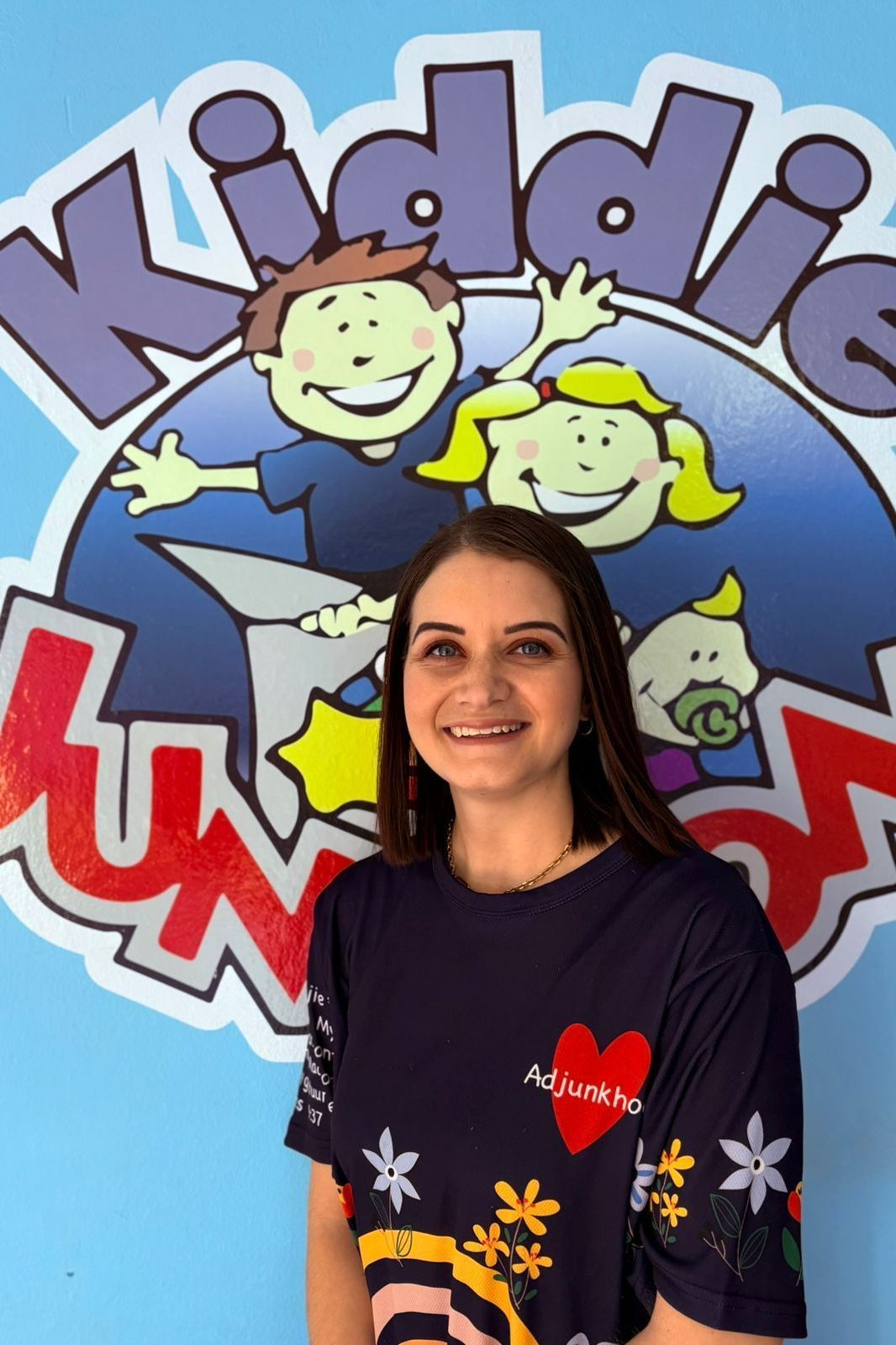 Woman in a navy shirt smiles in front of a 