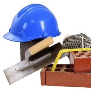 utensili e materiali da lavoro come casco, spatola, metro, mattoni forati