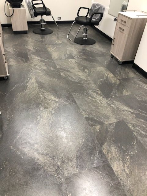 A salon with a gray tile floor and two chairs