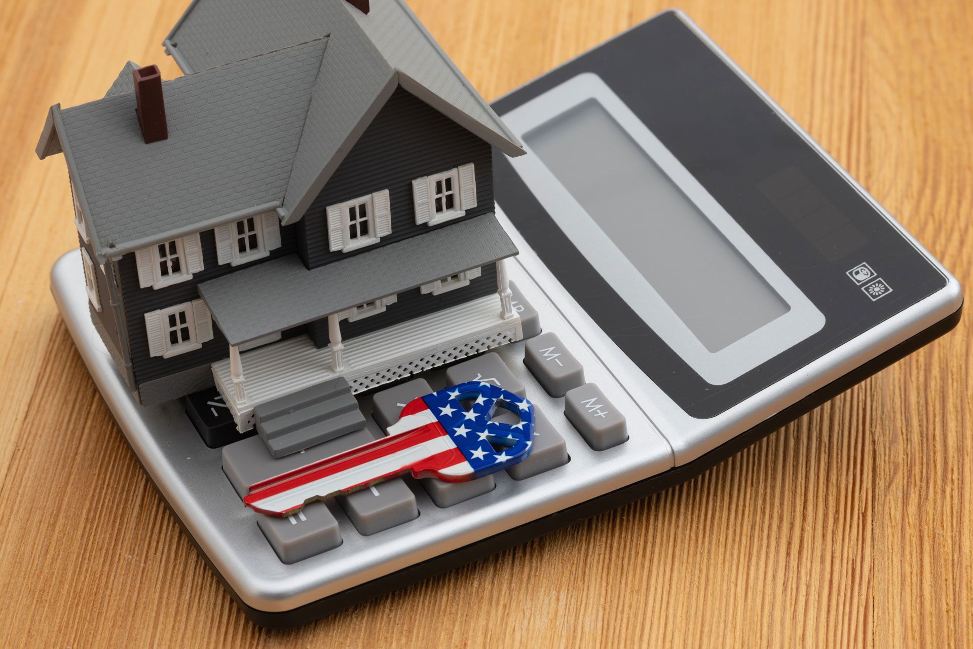 Toy house on a digital scale, with an American flag and small objects on the weighing platform.