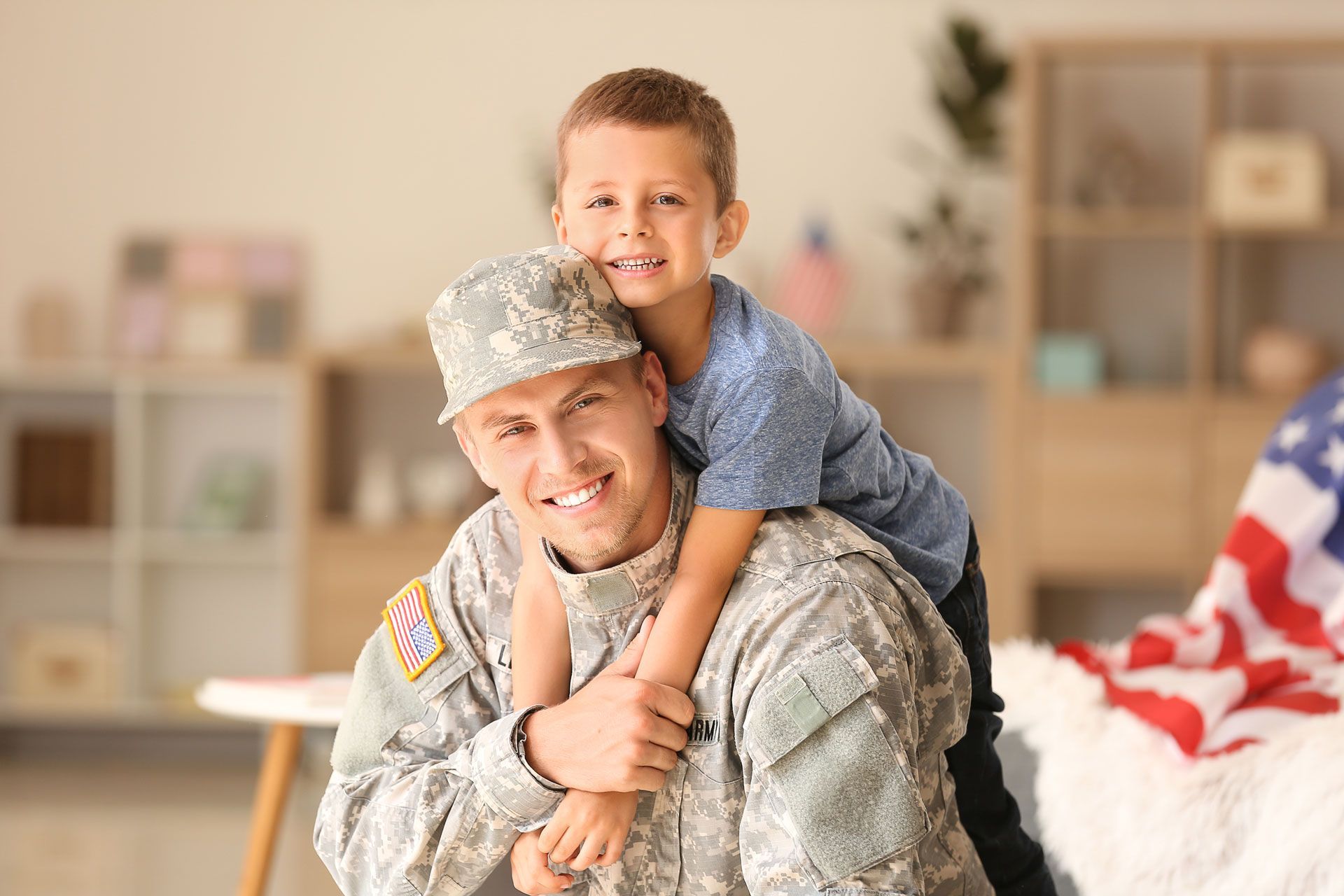Soldier smiling with a child on his back in a bright living room