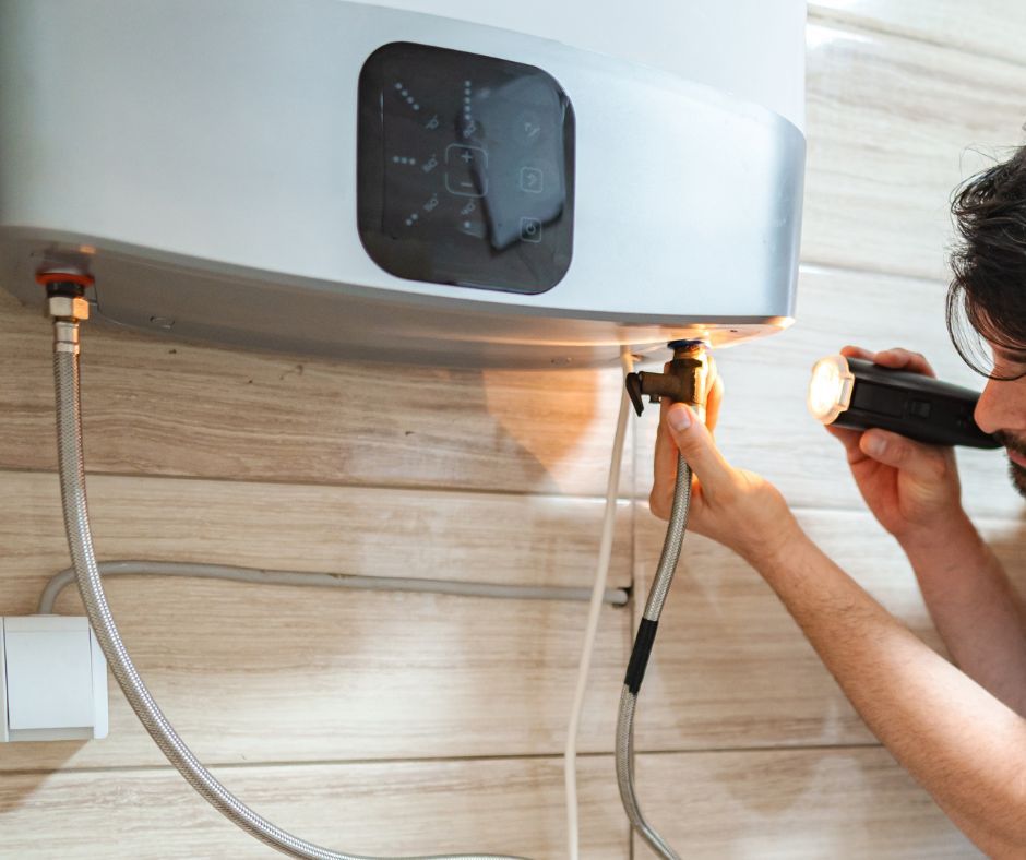 A professional plumber inspecting a wall-mounted water heater and pipes under a sink.