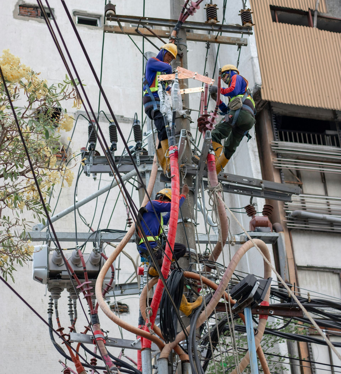 Technician working on a complex electrical panel in hard hat.