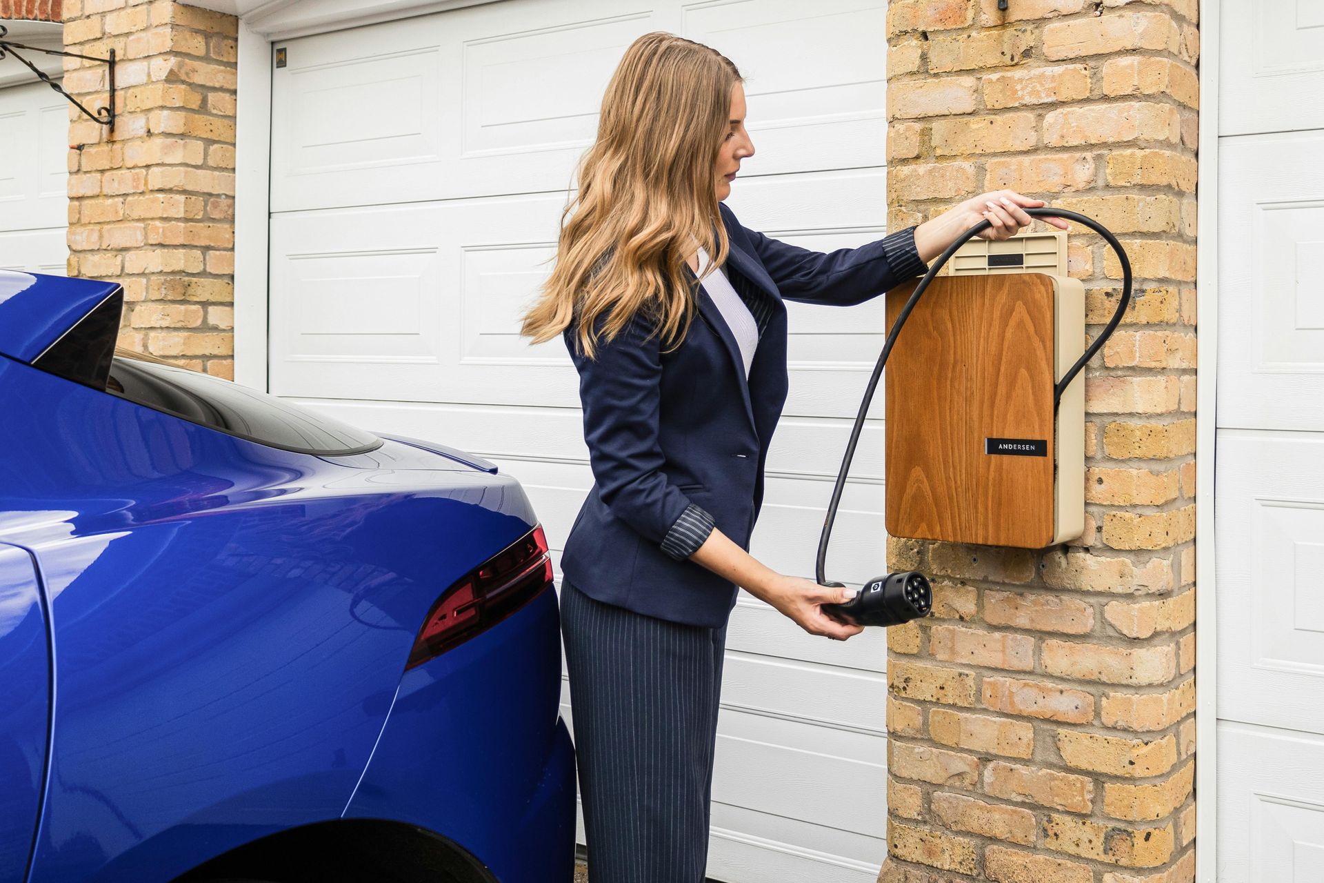 Woman installing an electric vehicle wall charger at home.