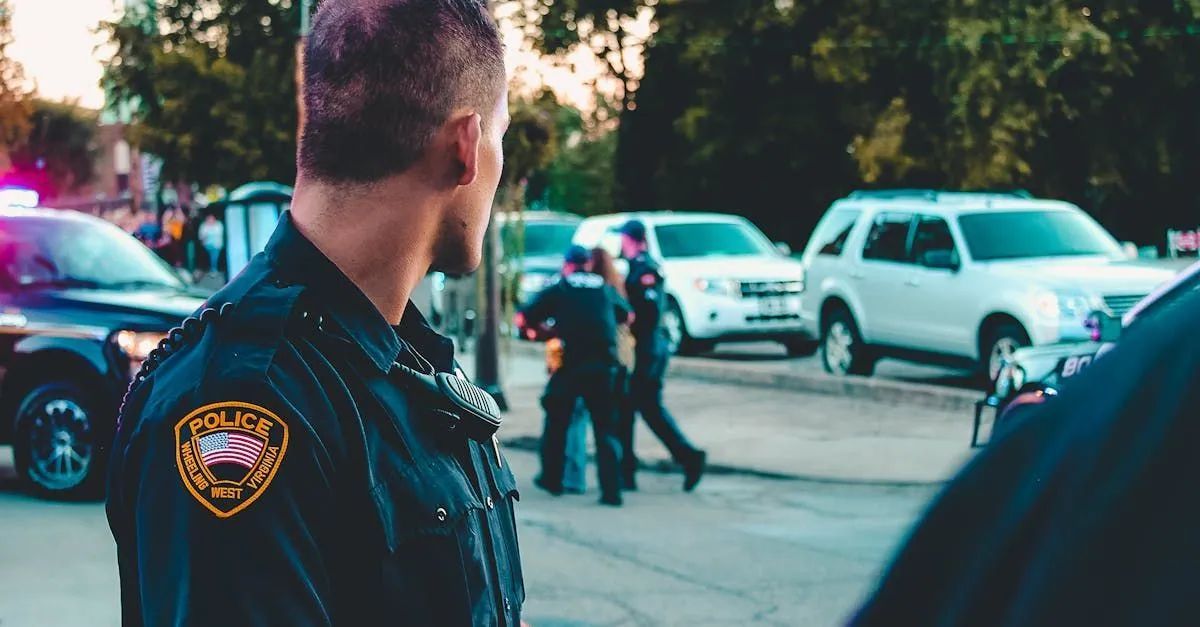 A police officer is standing in front of a crowd of people.