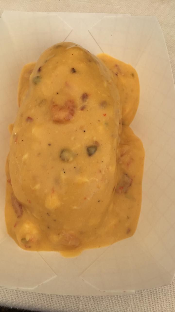 Creamy yellow dip with specks of green and red, on a white paper tray.