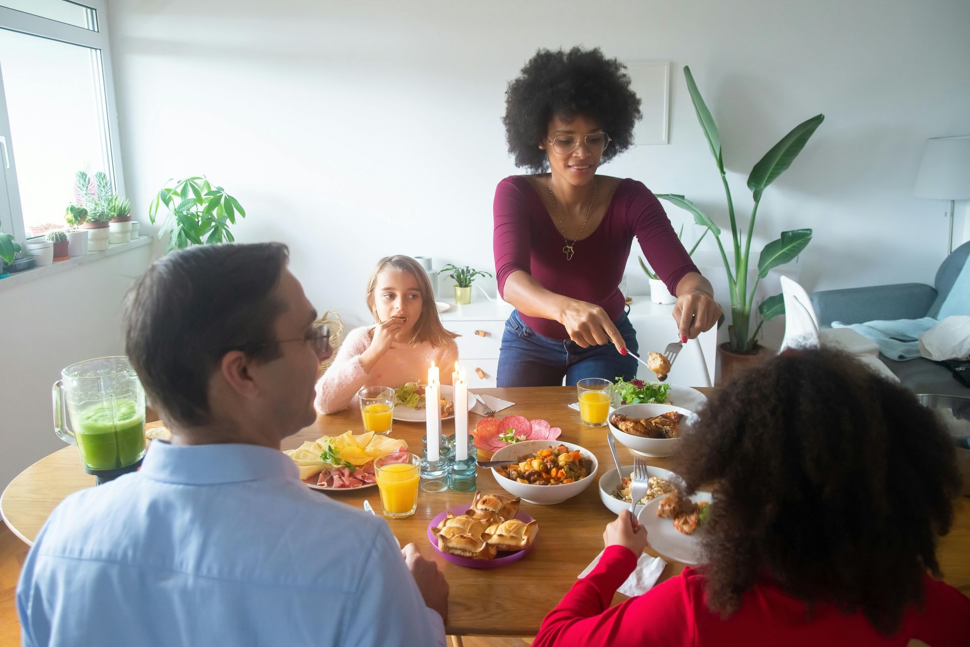 Family eating dinner at a round table; woman serving food.