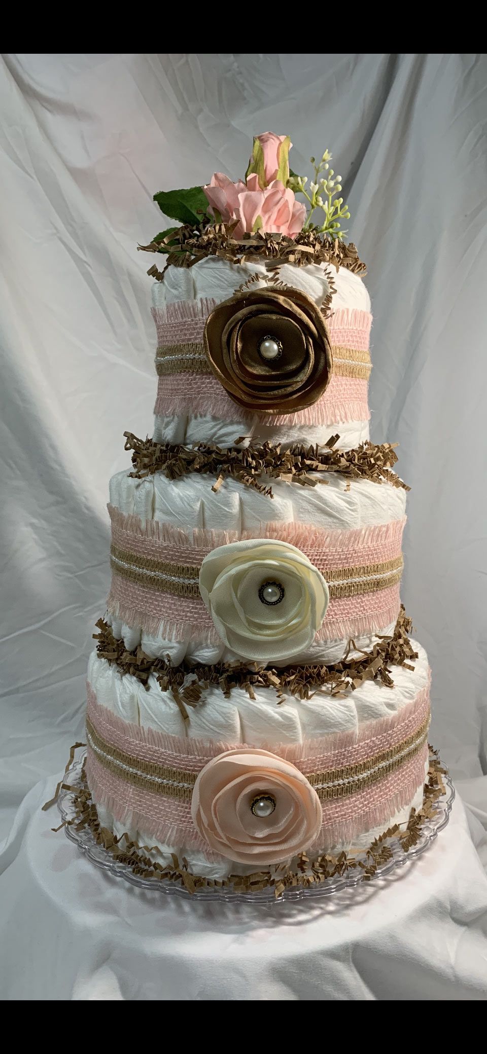 Three-tiered diaper cake decorated with pink, brown, and gold accents