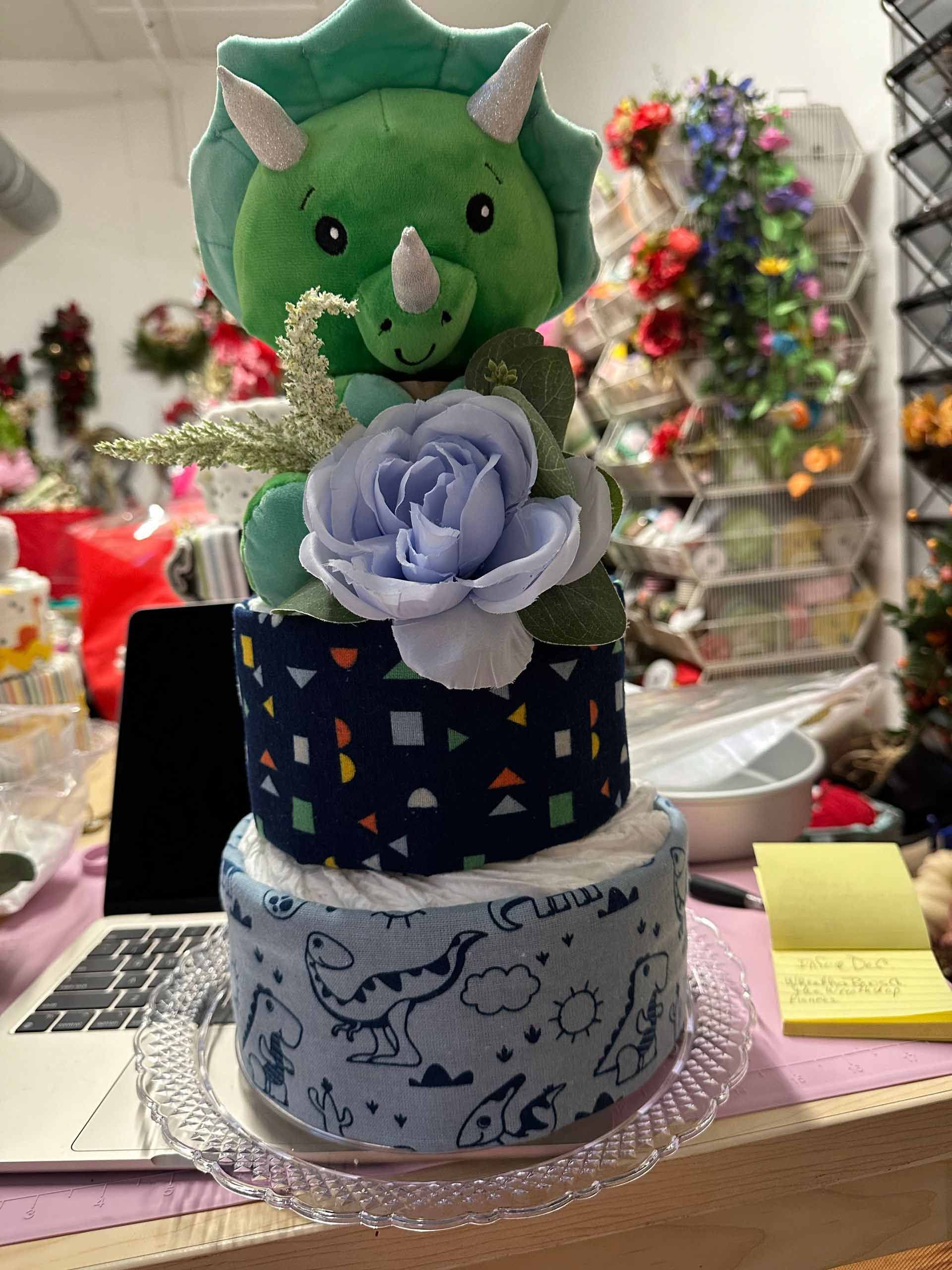 Diaper cake decorated with a green stuffed dinosaur