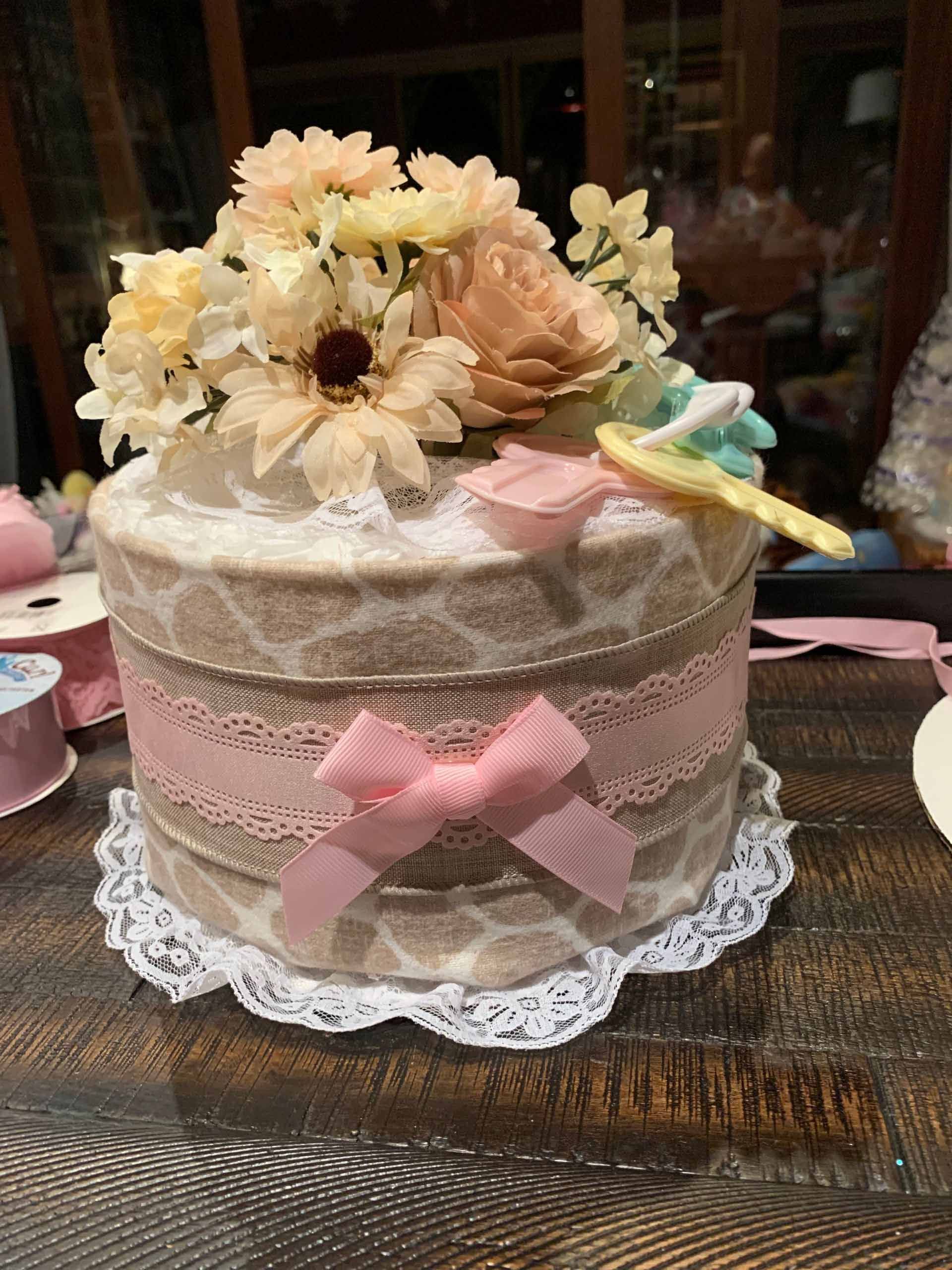 Diaper cake decorated with lace, ribbon, and flowers