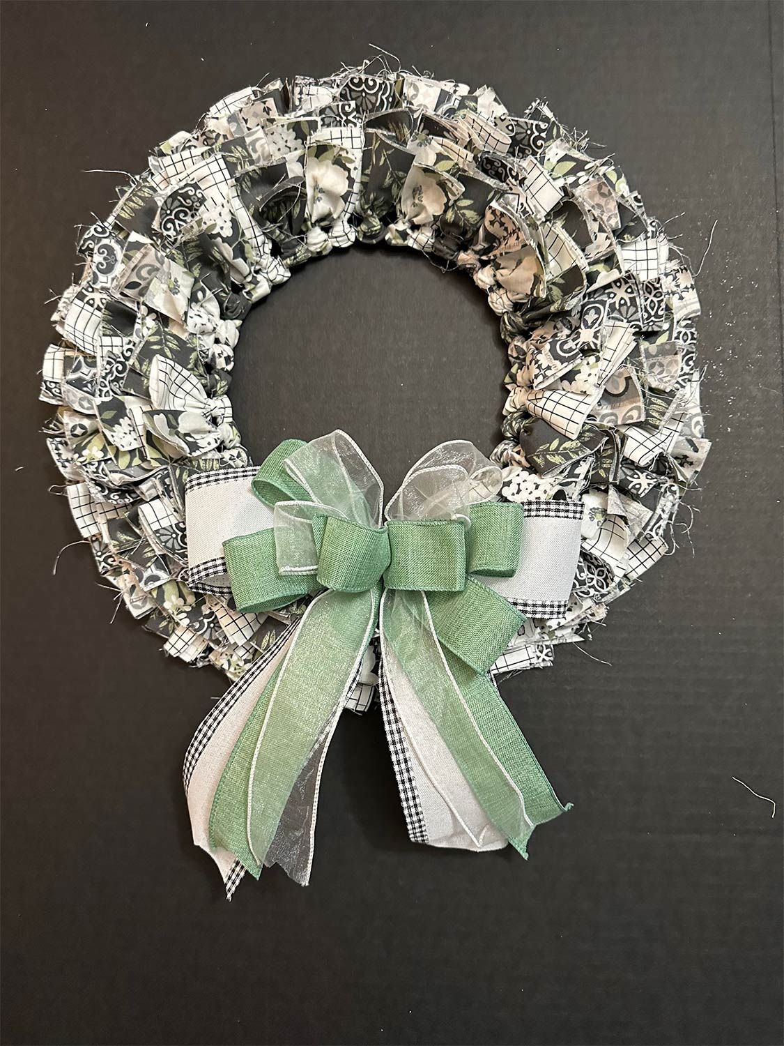 Wreath with black and white fabric, decorated with a green and white bow