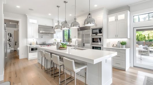 Bright modern kitchen with white island, pendant lights, stainless appliances, and wood floors