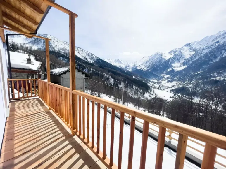 Una mano che mescola un cappuccino schiumoso in una tazza nera Mado, un croissant e dei bicchieri d'acqua su un tavolo.