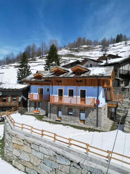 Una mano che mescola un cappuccino schiumoso in una tazza nera Mado, un croissant e dei bicchieri d'acqua su un tavolo.