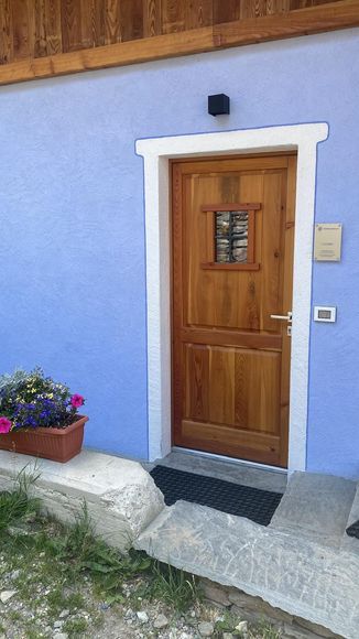 Una mano che mescola un cappuccino schiumoso in una tazza nera Mado, un croissant e dei bicchieri d'acqua su un tavolo.