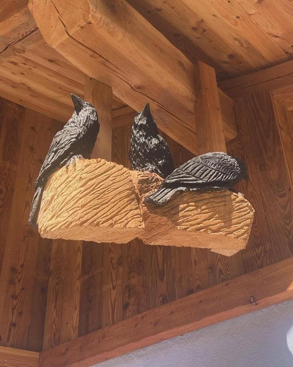 Una mano che mescola un cappuccino schiumoso in una tazza nera Mado, un croissant e dei bicchieri d'acqua su un tavolo.