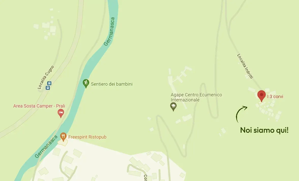 Una mano che mescola un cappuccino schiumoso in una tazza nera Mado, un croissant e dei bicchieri d'acqua su un tavolo.