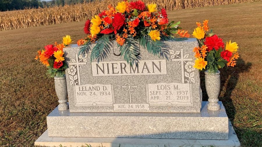 A white building with a sign in front of it is sitting on top of a lush green field.