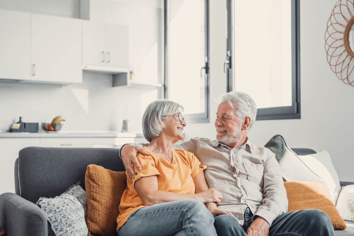 An elderly couple is sitting on a couch in a living room.
