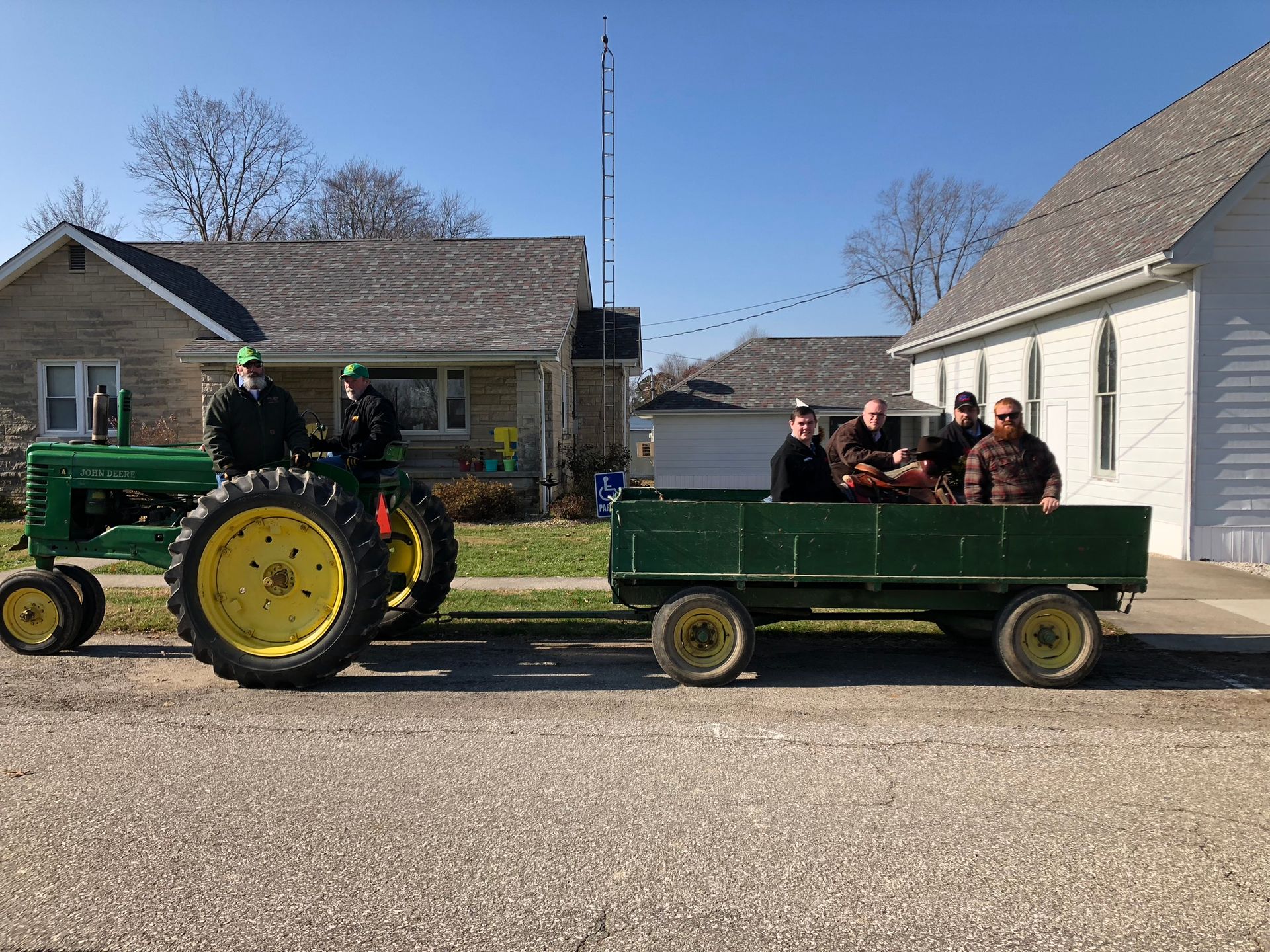A white building with a sign in front of it is sitting on top of a lush green field.