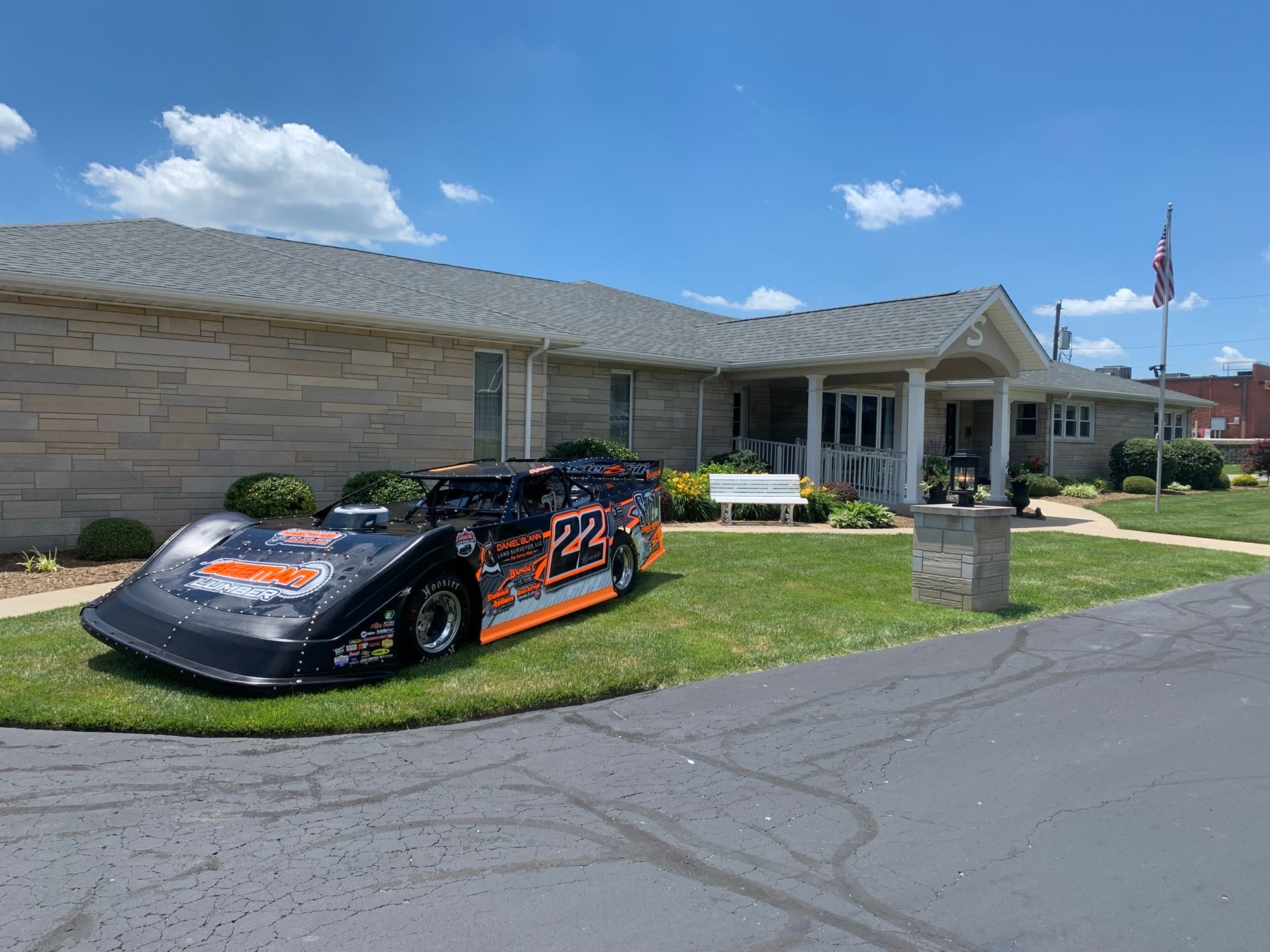 A white building with a sign in front of it is sitting on top of a lush green field.