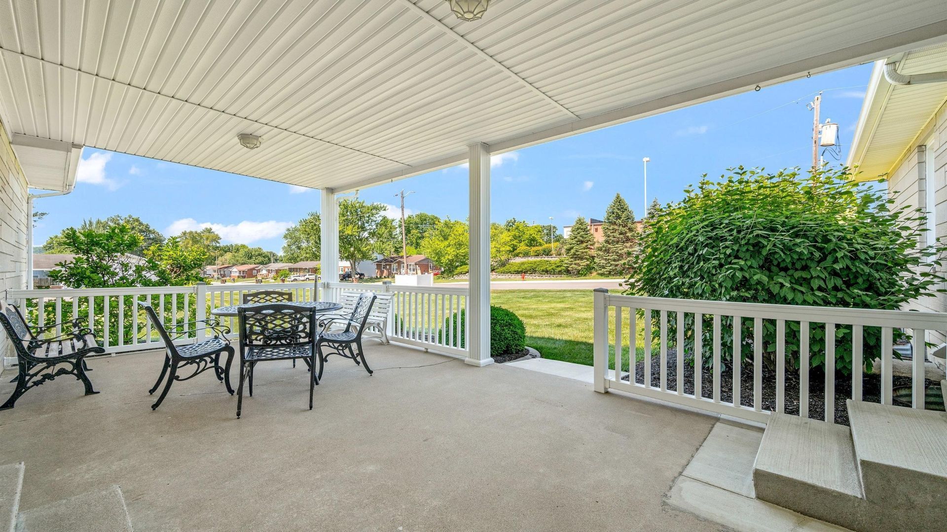 A white building with a sign in front of it is sitting on top of a lush green field.