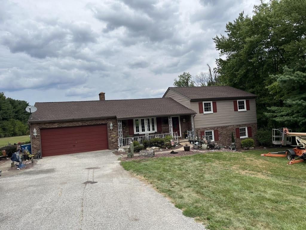 A large house with a red garage door and a tractor parked in front of it.