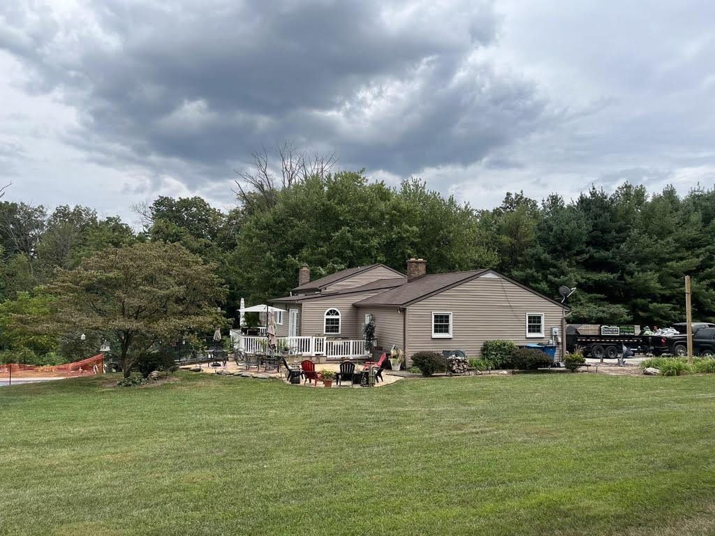 A house is sitting in the middle of a lush green field.