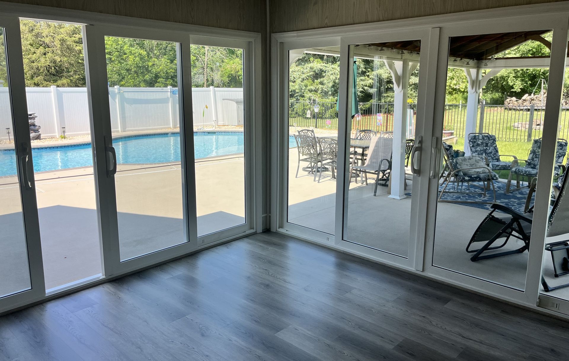 The corner of a room with all new floor-to-ceiling glass windows and doors. 
