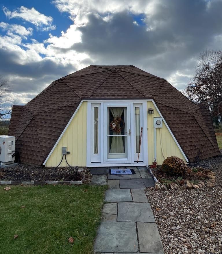 A dome shaped house with a brown roof and a white door