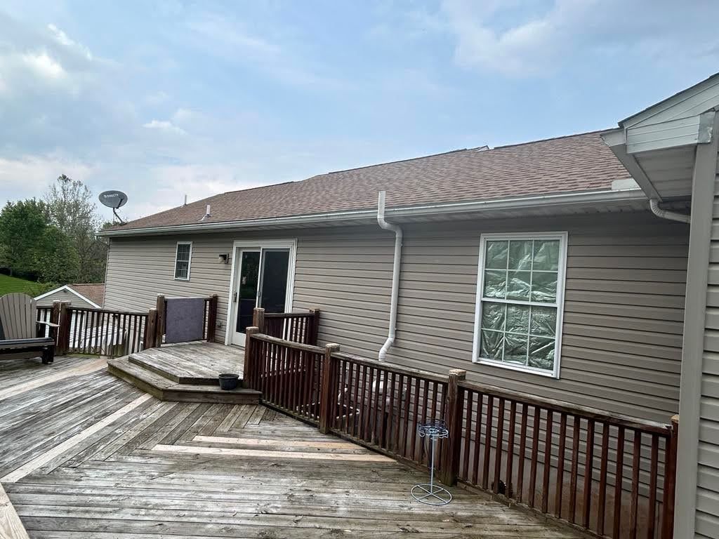 The back of a house with a wooden deck and a fence.