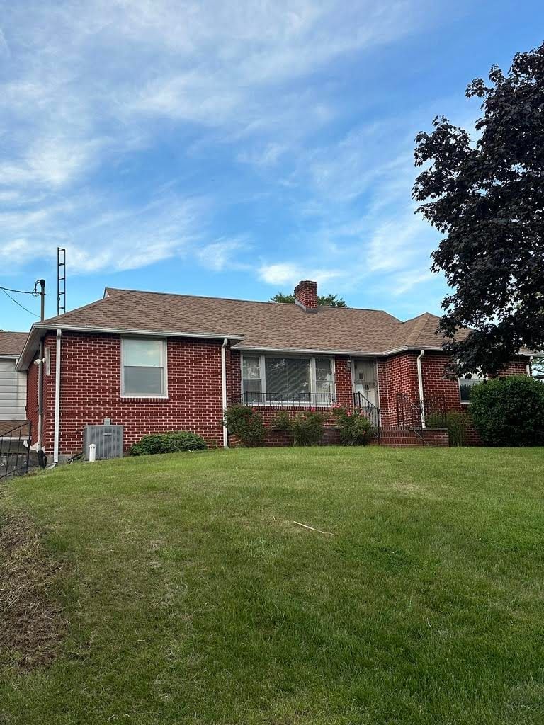A red brick house with a large lawn in front of it.