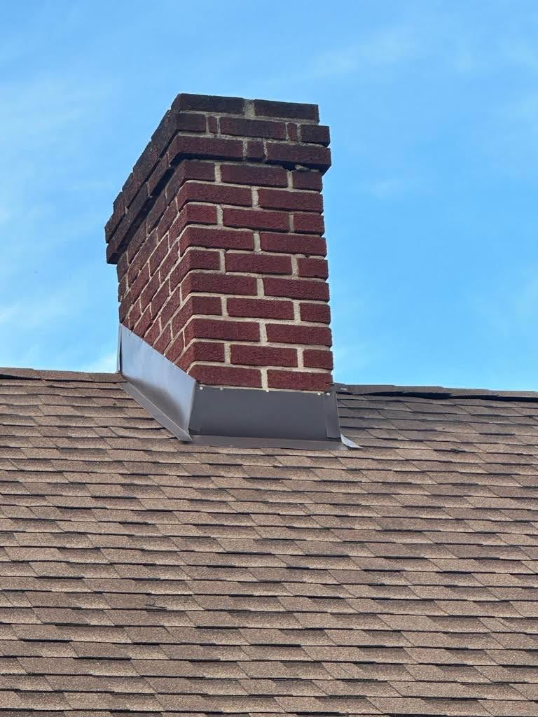 A brick chimney is sitting on top of a roof.