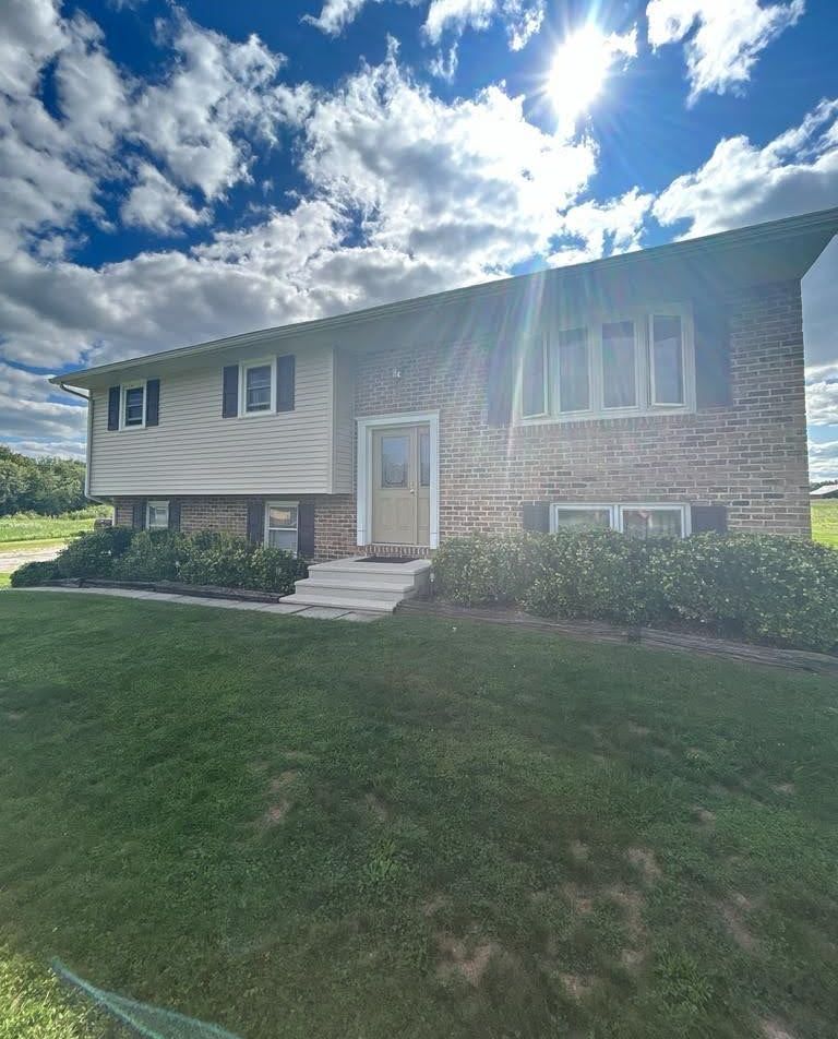 A large brick house with a large lawn in front of it.