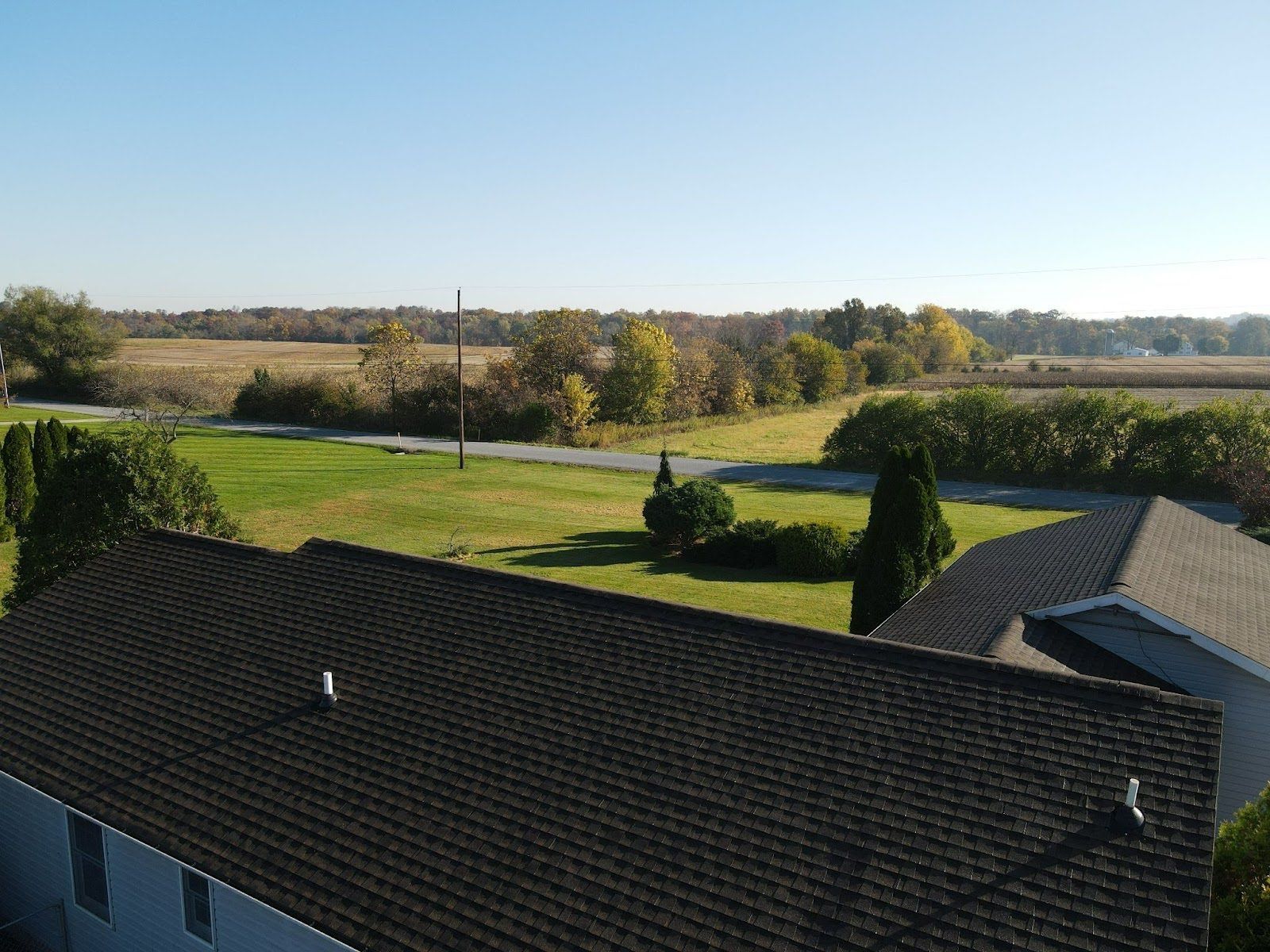 An aerial view of a house with a roof and a field in the background.