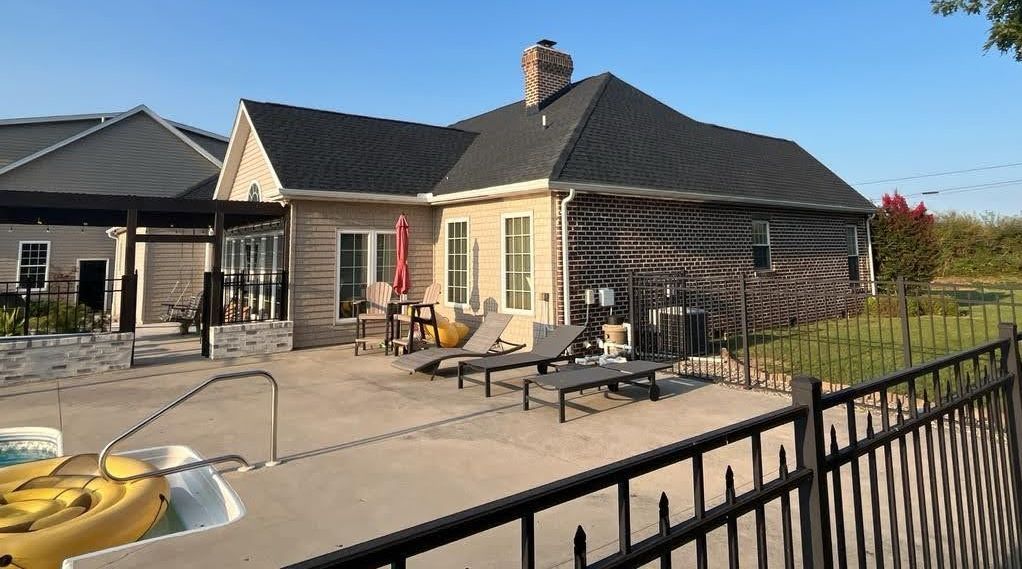A large house with a fence around it and a swimming pool in front of it.