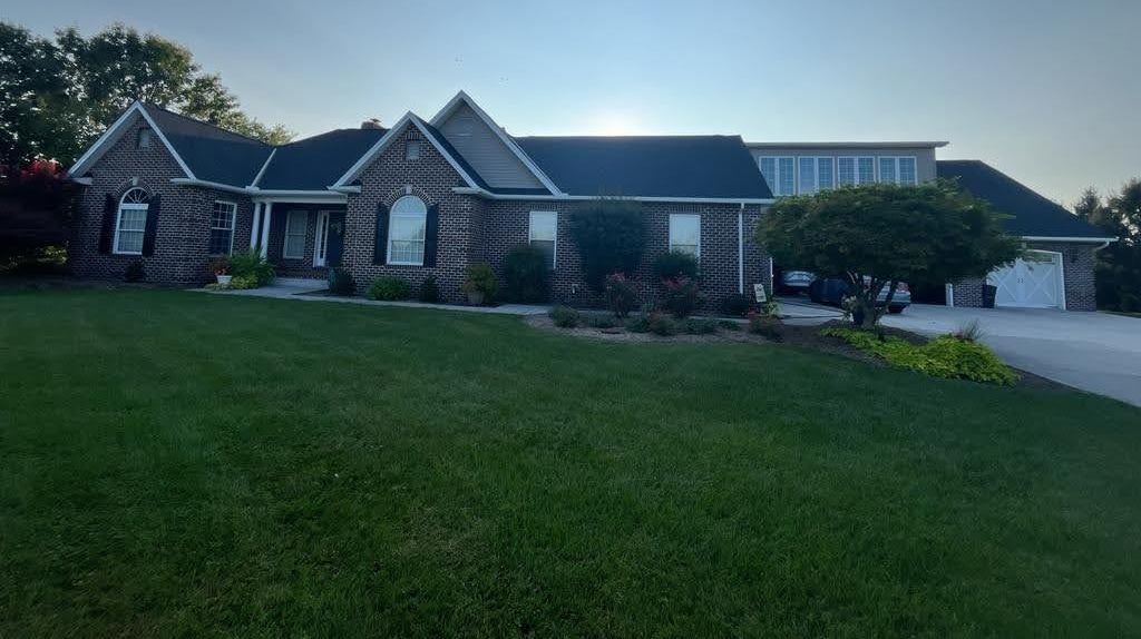 A large brick house with a large lawn in front of it.