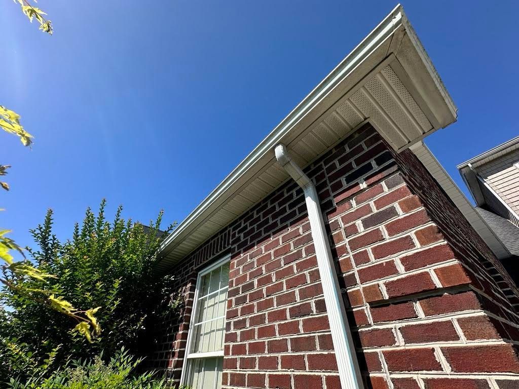 A brick house with a white gutter on the side of it.