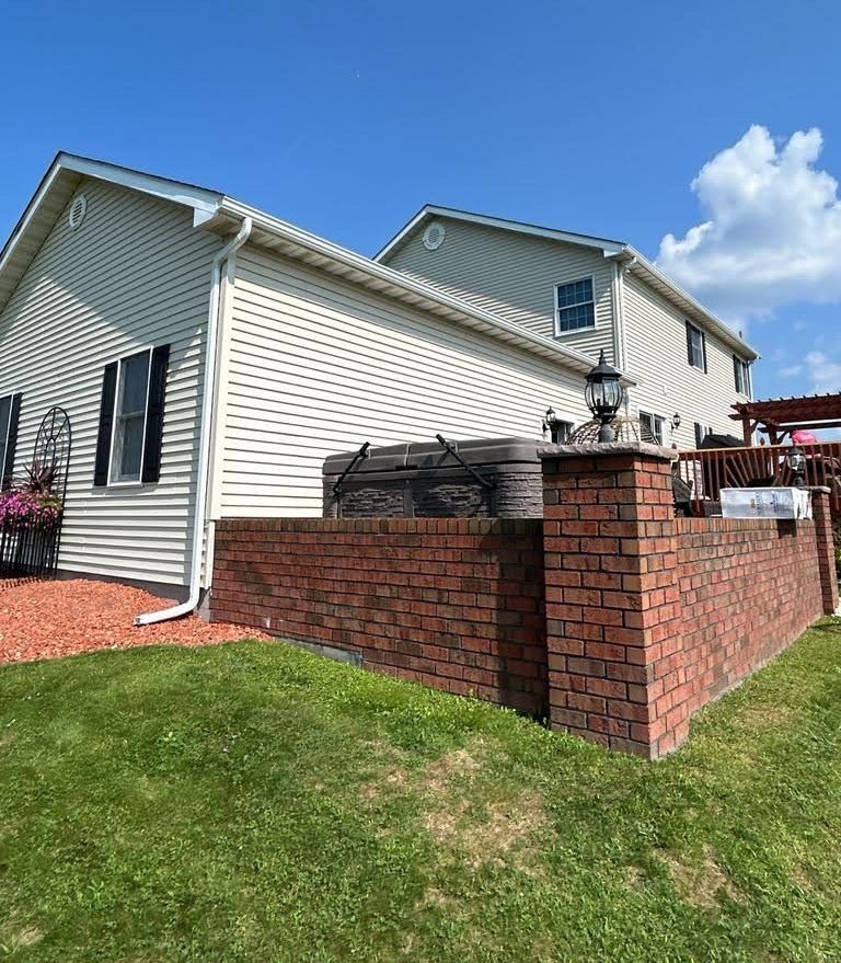 A white house with a brick wall in front of it.