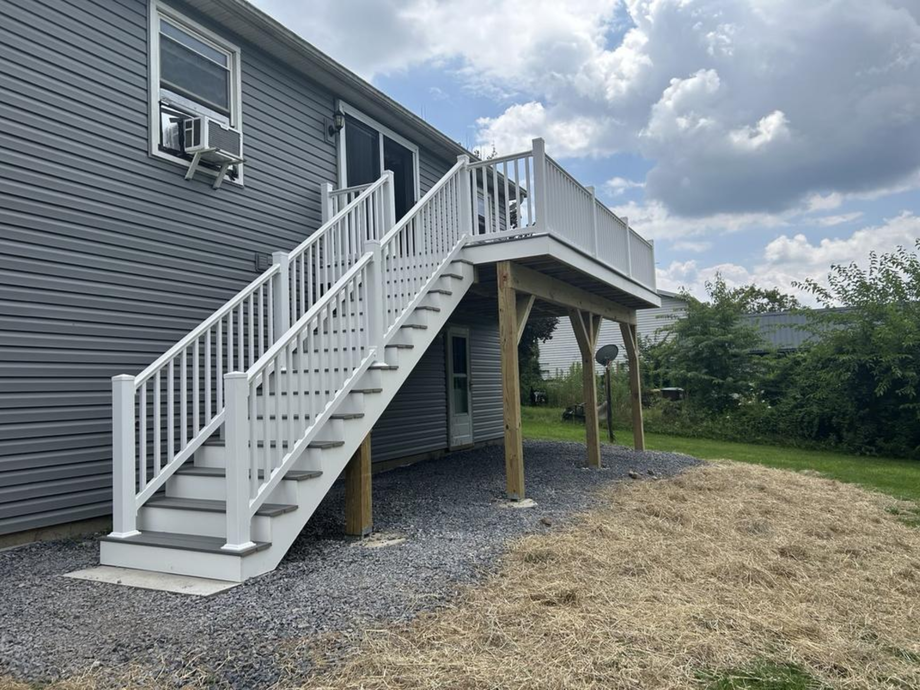 A beautiful gray home with a second-story deck addition and pristine white railings done by Dayhoff Construction.