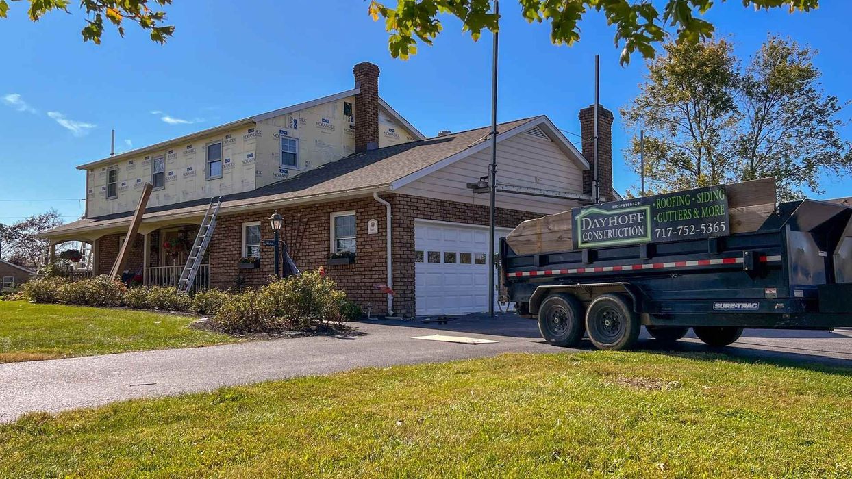 A dump truck is parked in front of a large house.