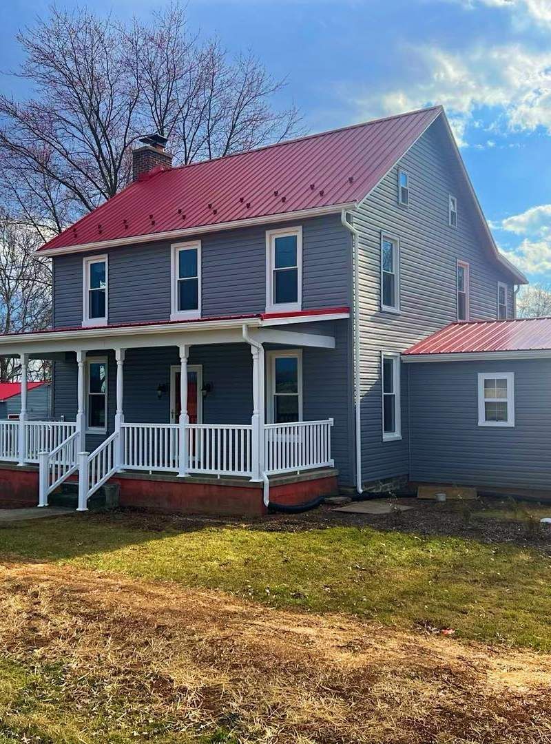 A gray house with a red roof and a porch.