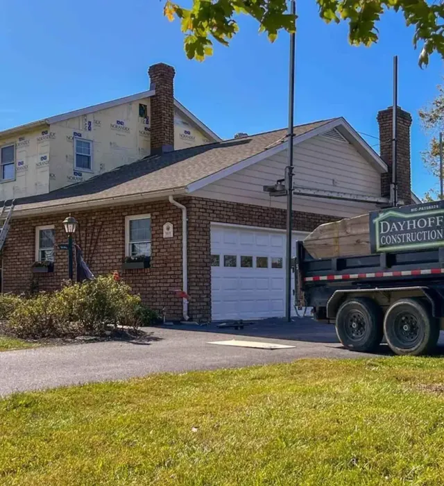 A dump truck is parked in front of a large house.