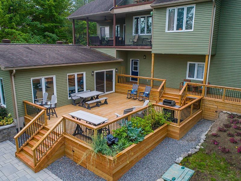An aerial view of a large brick house with a gray roof surrounded by trees.