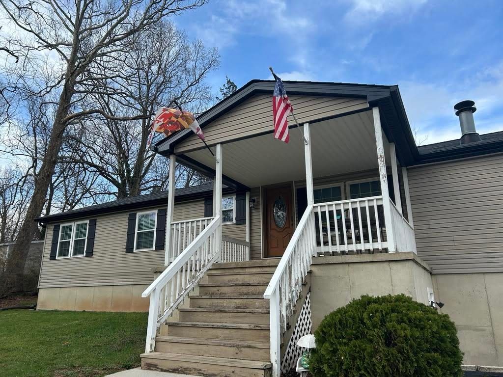 A mobile home with a porch and stairs and an american flag on it.