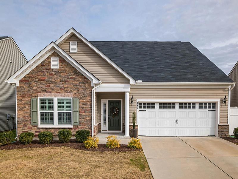 An aerial view of a large brick house with a gray roof surrounded by trees.