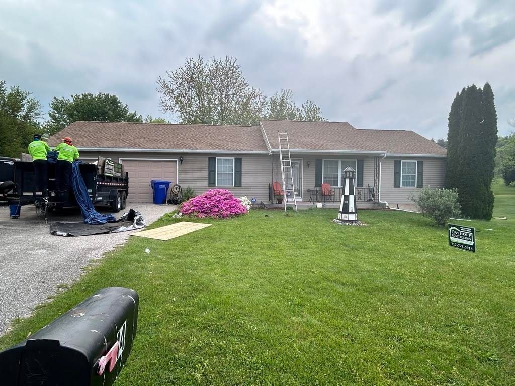 A group of people are working on the roof of a house.